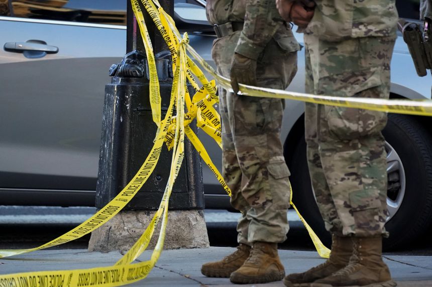 National Guard members stand together behind yellow tape, after two National Guard members were shot near the White House in Washington, DC, on November 26, 2025.